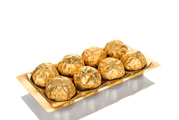 Several chocolate candies wrapped in gift paper, close-up, isolated on a white background.