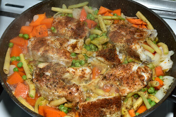 Cod cut into pieces is cooked in a frying pan together with vegetables.