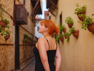 Young woman in elegant black dress walking in cozy old town Keleci, Antalya, Turkey during summer day. female traveler discover interesting places and popular attractions