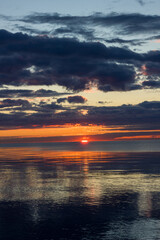 Orange sunrise with dark clouds on the shore. Lake Ladoga.