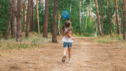 A child catches a butterfly in the park. Summer activity, nature.