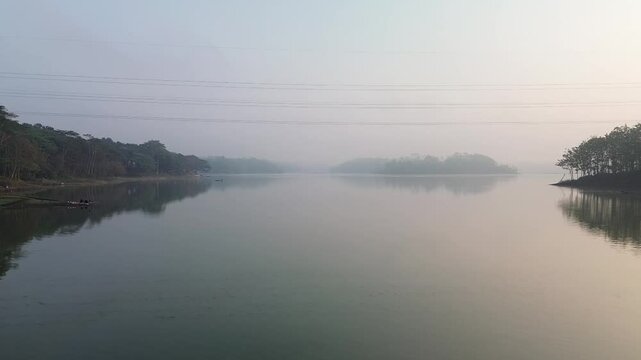 4k footage of a lake with calm water in the morning, covered in a thin mist