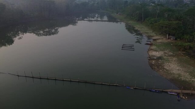 4k footage of a lake with calm water in the morning, covered in a thin mist