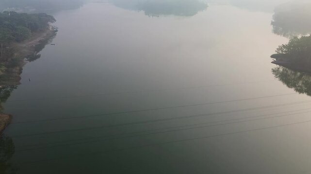 4k footage of a lake with calm water in the morning, covered in a thin mist