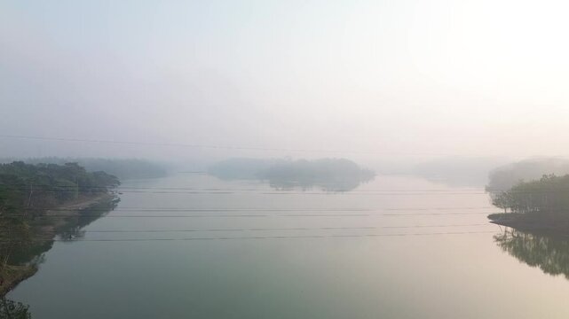 4k footage of a lake with calm water in the morning, covered in a thin mist