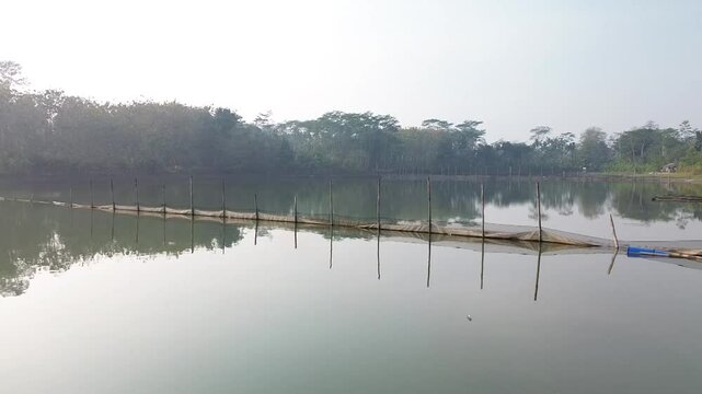 4k footage of a lake with calm water in the morning, covered in a thin mist