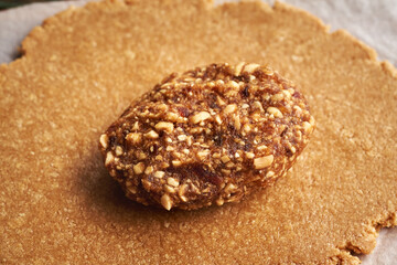 Rolled out dough made of whey protein powder and peanut butter with a ball of dates and nuts - ingredients for homemade protein bars