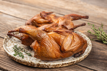 Smoked grilled quail meat with thyme on a wooden board