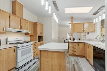 Modern kitchen with wooden cabinets and bright lighting featuring an island and dining area