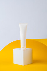 Cosmetic product in tube, bottle, lotion or serum on yellow background with stylish props. 