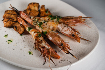 grilled shrimps with mushrooms and butter garlic saouce served on sticks topped by mediterranean herbs close up
