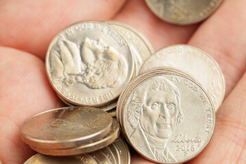 A hand is holding a pile of silver coins