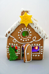 A handmade decorated gingerbread Christmas house photographed on a white background with Christmas...