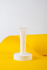 Plastic white tube for cream or lotion. Skin care or sunscreen cosmetic on yellow background.