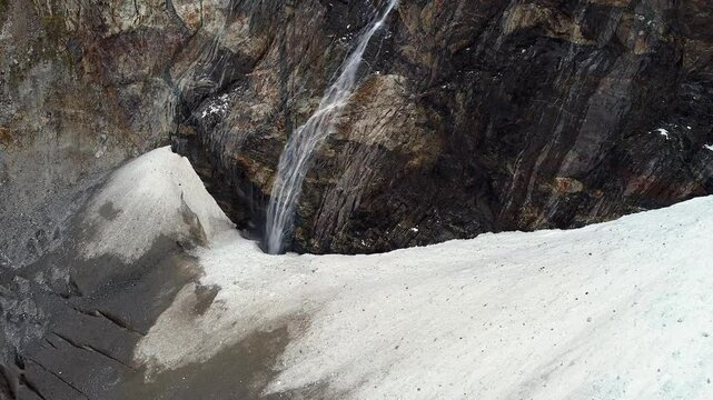 Waterfall drops into bergschrund crevasse of Adishi Glacier in Georgia