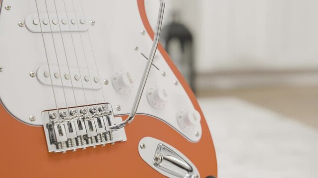 Close up of a red Stratocaster style electric guitar in a living room