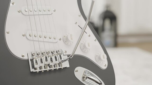 Close up of a black Stratocaster style electric guitar in a living room