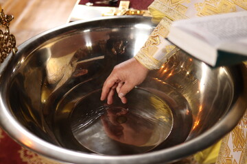 The priest blesses the water on the baptismal font in the church. The Sacrament of Baptism in Christianity.without a face. 