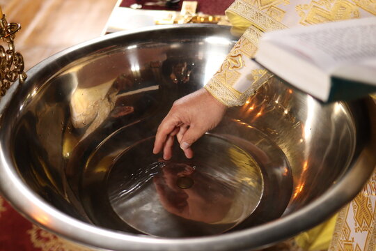 The priest blesses the water on the baptismal font in the church. The Sacrament of Baptism in Christianity.without a face. 