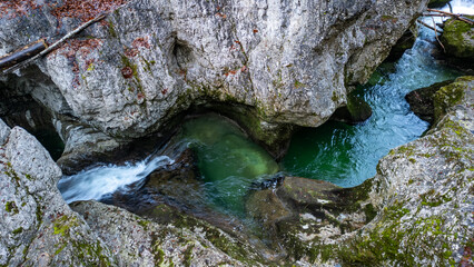 Obraz premium A stream and waterfall in the Walchenklamm gorge in the Bavarian Forest in late autumn. Rocks covered in moss and trees without leaves. mysterious and enigmatic, aerial View