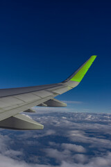 A high-resolution photo of a plane wing and blue sky viewed through an airplane window, symbolizing aviation, travel, vacations, and early booking opportunities