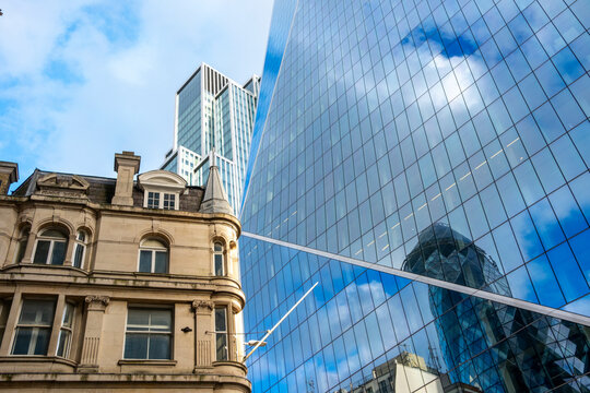 This image captures the reflection of skyscrapers on a historical building, highlighting the blend of contemporary design with classic architecture elements in London UK