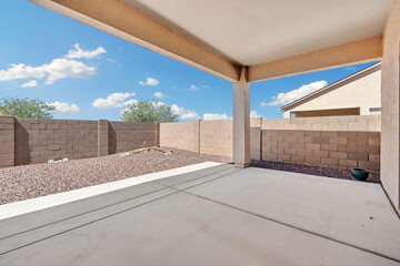 Spacious backyard patio with clear blue skies and surrounding walls in a residential neighborhood