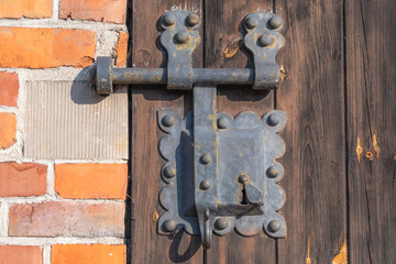 a rustic door lock featuring an ornate, weathered metal design attached to a wooden door