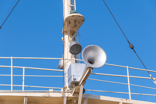a ship's upper deck featuring metal structures such as a large loudspeaker, light fixtures, and railings