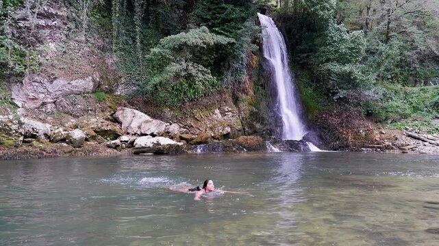 Woman swims in shallow pool below Abhesi Waterfall at Martvili Georgia