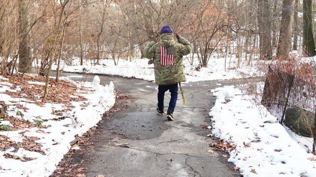 A young man, lost in thought, pauses at a fork in a snow-covered path. He removes his headphones and contemplates his next move as the winter landscape stretches out before him.