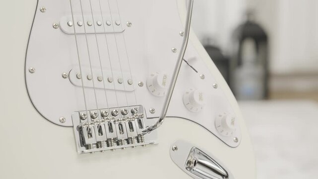 Close up of a white Stratocaster style electric guitar in a living room