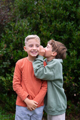Two boys sharing secrets in a whispering conversation outdoors