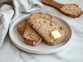 Fototapeta premium Slices of whole grain bread with a pat of butter on a plate.