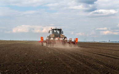 Fototapeta premium Farmer with tractor seeding in sunset