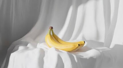 Fresh and Ripe Bananas on a Soft White Fabric with Elegant Natural Light Creating Gentle Shadows and Highlights for a Minimalist Visual Appeal