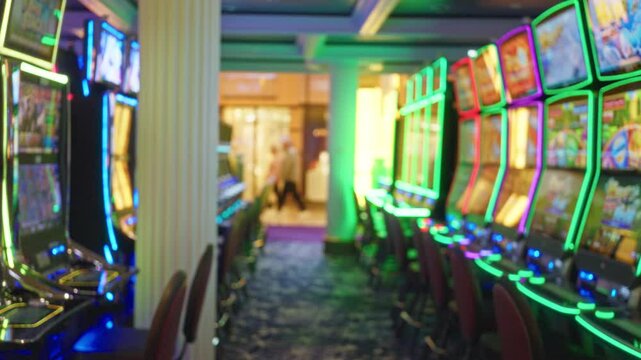Blurred view of a vibrant las vegas casino interior featuring colorful slot machines lined up in a defocused manner, creating a lively nightlife atmosphere.