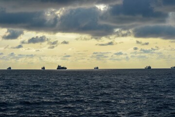 Fototapeta premium Serene Seascape with Cargo Ships and Dramatic Cloudy Sky