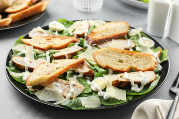 Delicious Caesar salad with chicken on grey textured table, closeup