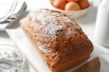 Tasty sponge cake with ingredients on white table, closeup