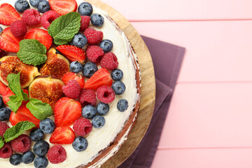 Delicious chocolate sponge cake with berries on pink wooden table, top view. Space for text