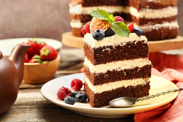 Piece of delicious chocolate sponge cake with berries served on wooden table, closeup