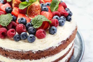 Delicious chocolate sponge cake with berries on white table, closeup