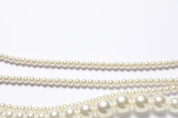Beautiful pearl necklaces on white background, flat lay. Space for text