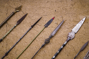 A collection of antique spears displayed against a textured backdrop. These historical artifacts...