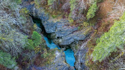 A stream and waterfall in the Walchenklamm gorge in the Bavarian Forest in late autumn. Rocks covered in moss and trees without leaves. mysterious and enigmatic, aerial View