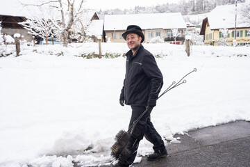 A chimney sweep walks through a snow-covered neighborhood, carrying tools. The image captures a...