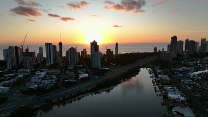 The Gold Coast's Surfers Paradise dazzles at sunrise with high-rises glowing in golden-pink hues, pristine beaches, shimmering ocean, and surfers, blending urban energy with natural beauty.