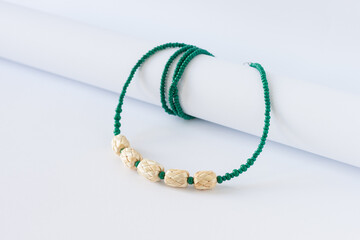 Straw and bead necklace, and green beaded bracelet on a white background. Green beaded. 