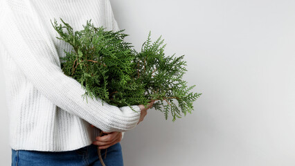 Winter and natural beauty,  woman in a white sweater holding thuja branches
